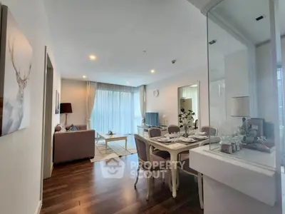Elegant living room with dining area, featuring modern decor and wooden flooring.