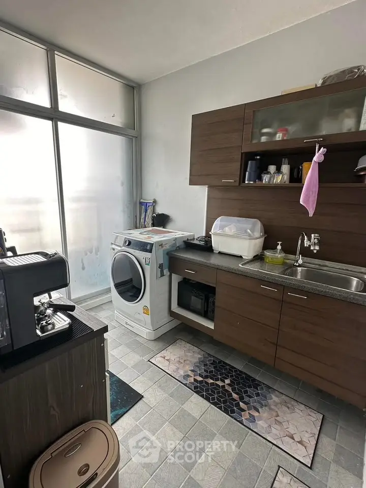 Modern kitchen with washing machine and sleek cabinetry in a bright, compact space.