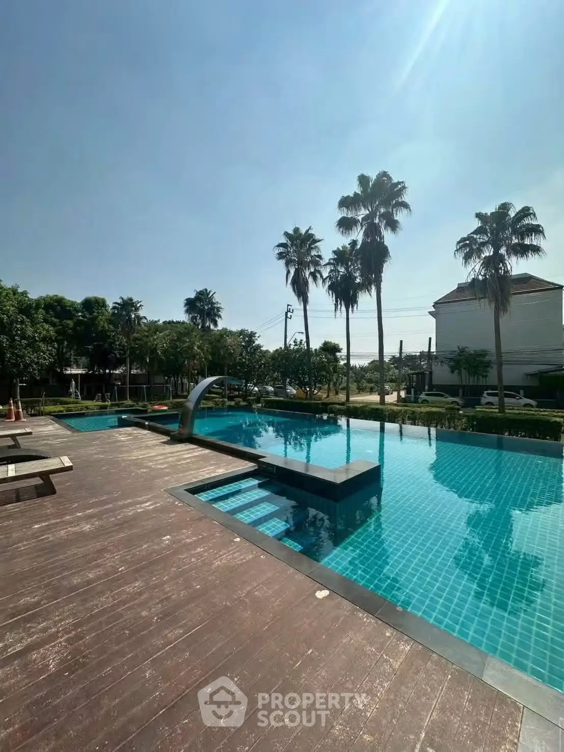 Luxurious outdoor pool area with palm trees and clear blue sky, perfect for relaxation and leisure.