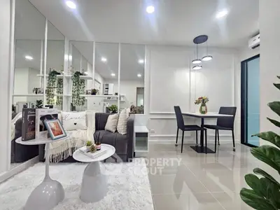 Modern living room with stylish decor and dining area, featuring elegant lighting and cozy seating.