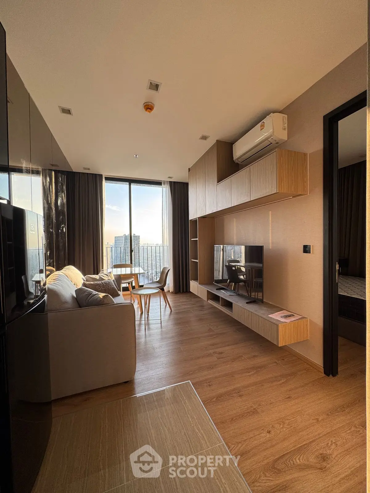 Modern living room with city view, featuring sleek furniture and wooden flooring.