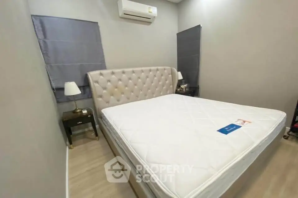 Cozy bedroom with elegant tufted headboard and modern air conditioning unit.