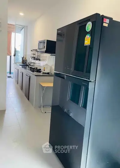 Modern kitchen with sleek black fridge and ample counter space in a bright, airy setting.