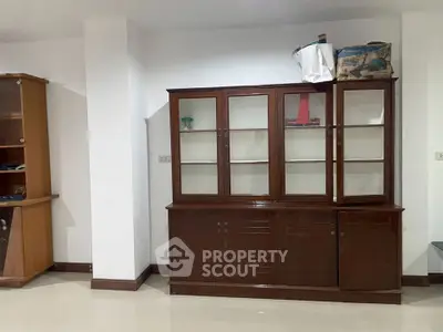 Spacious living room with elegant wooden cabinets and glossy tiled flooring.