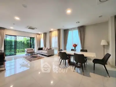 Spacious modern living room with elegant dining area and large windows offering garden views.