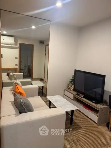 Cozy living room with modern decor and large mirror enhancing space.