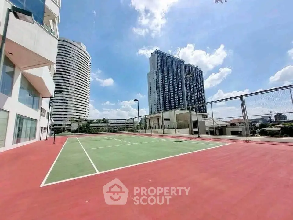 Stunning urban tennis court with high-rise buildings and clear blue sky view.