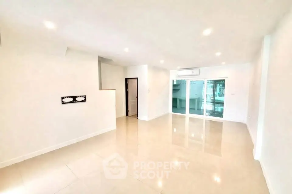 Spacious modern living room with glossy tile flooring and large windows for natural light.