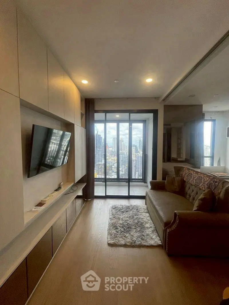 Modern living room with city view, featuring sleek built-in entertainment unit and cozy seating area.