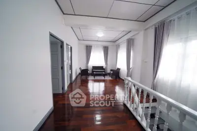 Spacious living area with polished wooden floors and elegant curtains