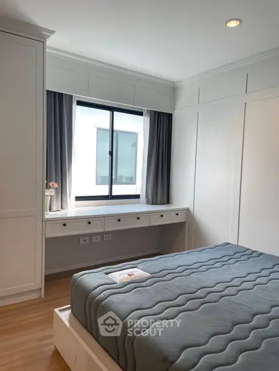 Modern bedroom with large window and stylish decor, featuring a comfortable bed and built-in storage.