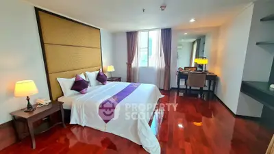 Luxurious bedroom with polished wooden floors, elegant decor, and ample natural light from large window.