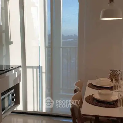 Modern kitchen with dining area and balcony view, featuring sleek appliances and stylish decor.