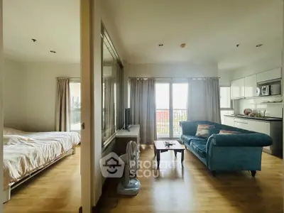 Spacious open-plan living room with cozy seating and modern kitchen in a bright apartment.