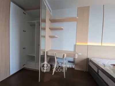 Modern bedroom with built-in wardrobe and study desk, featuring sleek wooden finishes and ambient lighting.