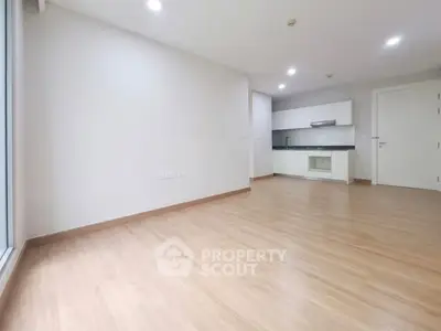 Spacious modern living room with open kitchen layout and sleek wooden flooring.