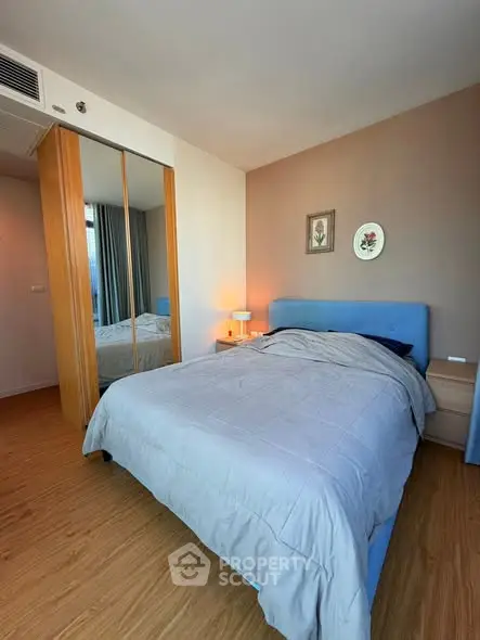 Modern bedroom with stylish decor and mirrored wardrobe in a cozy apartment.