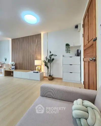 Modern living room with stylish decor and wooden accents, featuring a cozy sofa and ambient lighting.