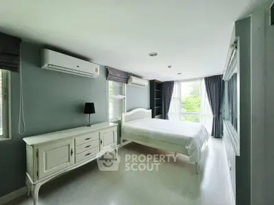 Spacious bedroom with large windows and elegant furnishings in modern apartment