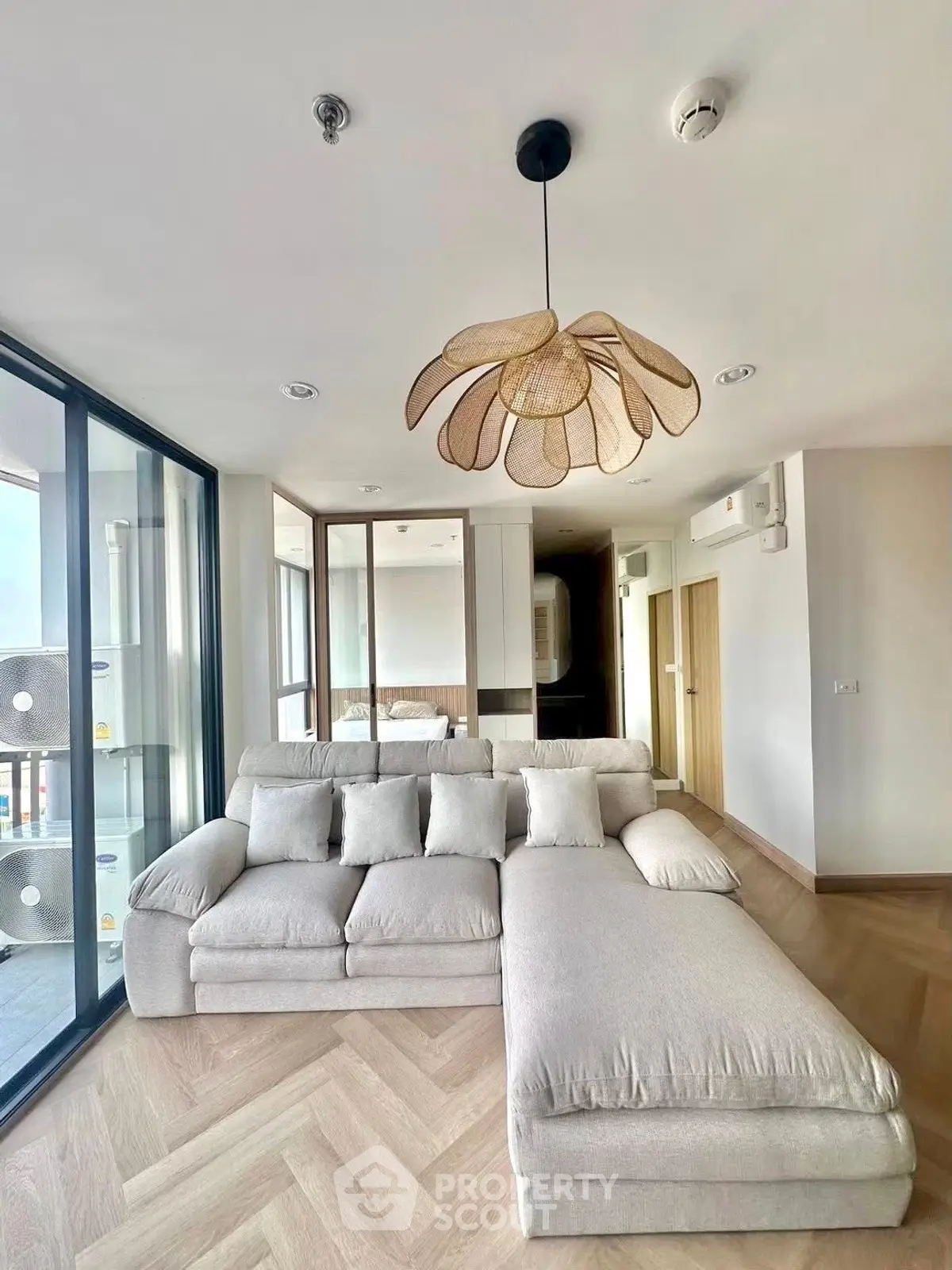 Spacious modern living room with elegant sectional sofa and stylish lighting, featuring floor-to-ceiling windows.
