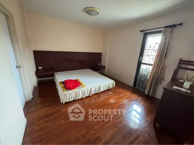 Spacious bedroom with wooden flooring and natural light, featuring a minimalist design and cozy atmosphere.