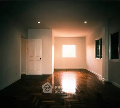 Spacious empty room with polished wooden floors and ample natural light.