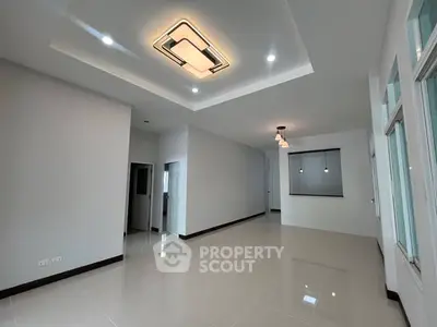 Spacious modern living room with elegant ceiling lights and large windows.