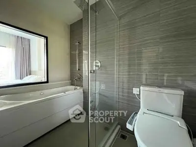 Modern bathroom with glass shower and sleek bathtub in luxury apartment.