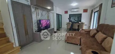 Modern living room with stylish furniture and TV, open dining area, and elegant decor.
