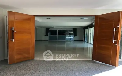 Spacious entrance with elegant wooden double doors leading to a bright interior space.