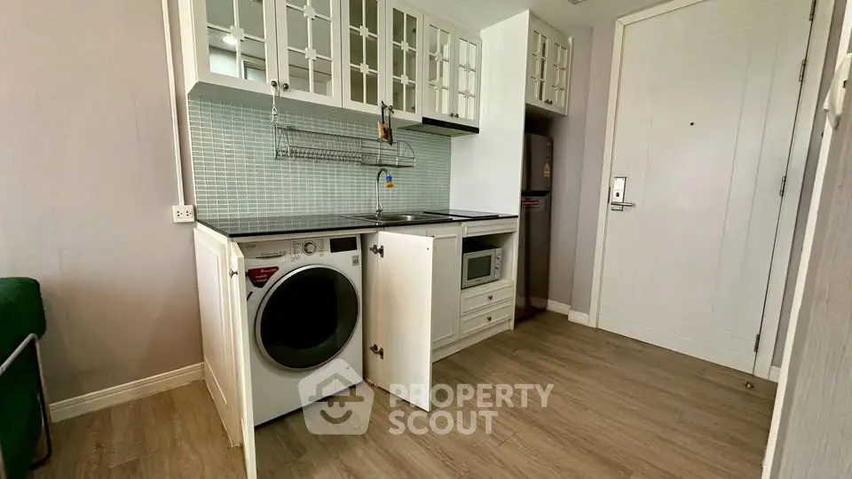 Compact kitchen with modern appliances and washing machine in stylish apartment