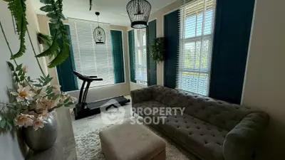 Charming living room with treadmill, elegant sofa, and large windows with shutters, perfect for relaxation and fitness.