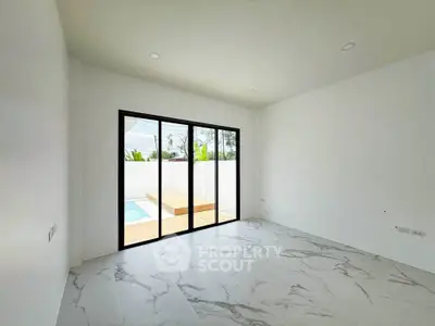 Spacious modern room with marble flooring and pool view through large glass doors.