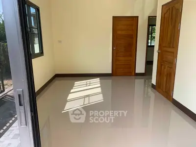 Spacious room with glossy tiled floor and wooden doors, perfect for customization.
