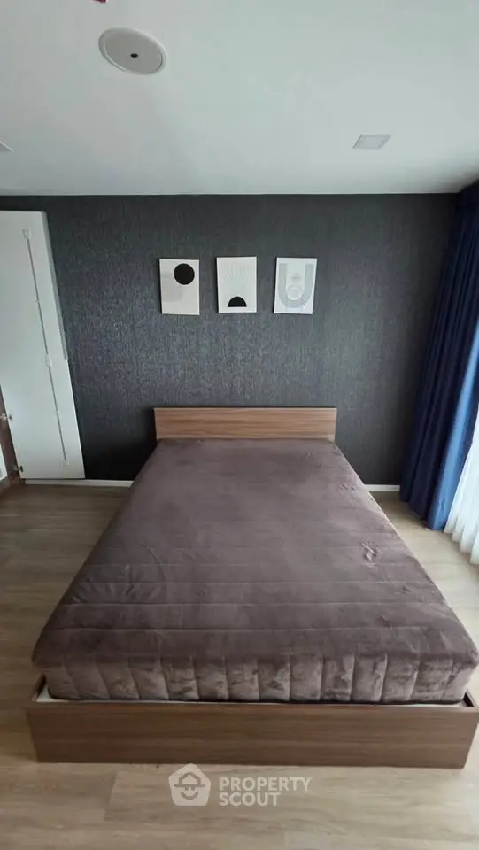 Modern bedroom with stylish decor and wooden flooring, featuring a cozy bed and contemporary wall art.