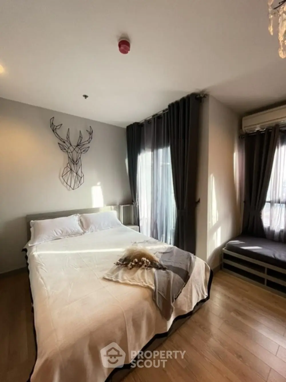 Cozy bedroom with modern decor and natural light, featuring a stylish deer wall art and elegant curtains.