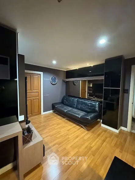 Modern living room with sleek black sofa and wooden flooring, perfect for contemporary urban living.