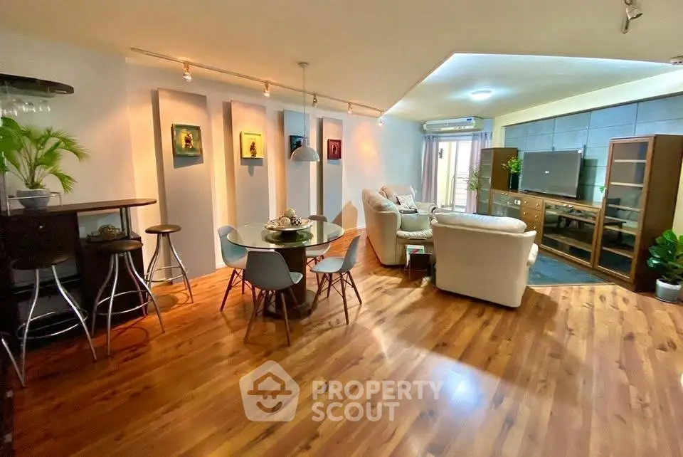 Spacious living room with modern decor and wooden flooring, featuring a cozy seating area and dining space.