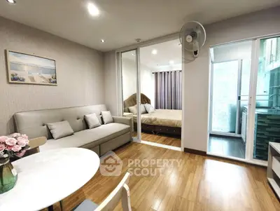 Modern living room with wooden flooring, cozy sofa, and view into a stylish bedroom.