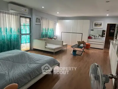 Spacious bedroom with modern decor and natural light, featuring a cozy seating area and ample storage.