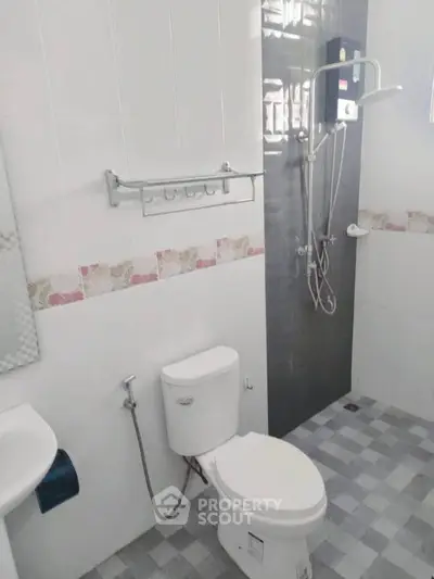 Modern bathroom with shower and toilet, featuring tiled walls and floor.