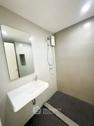 Modern minimalist bathroom with sleek shower and sink in contemporary apartment.