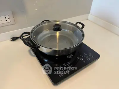 Modern kitchen with induction cooktop and stainless steel pot on white countertop