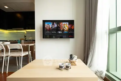 Modern living room with wall-mounted TV and stylish kitchen in open layout