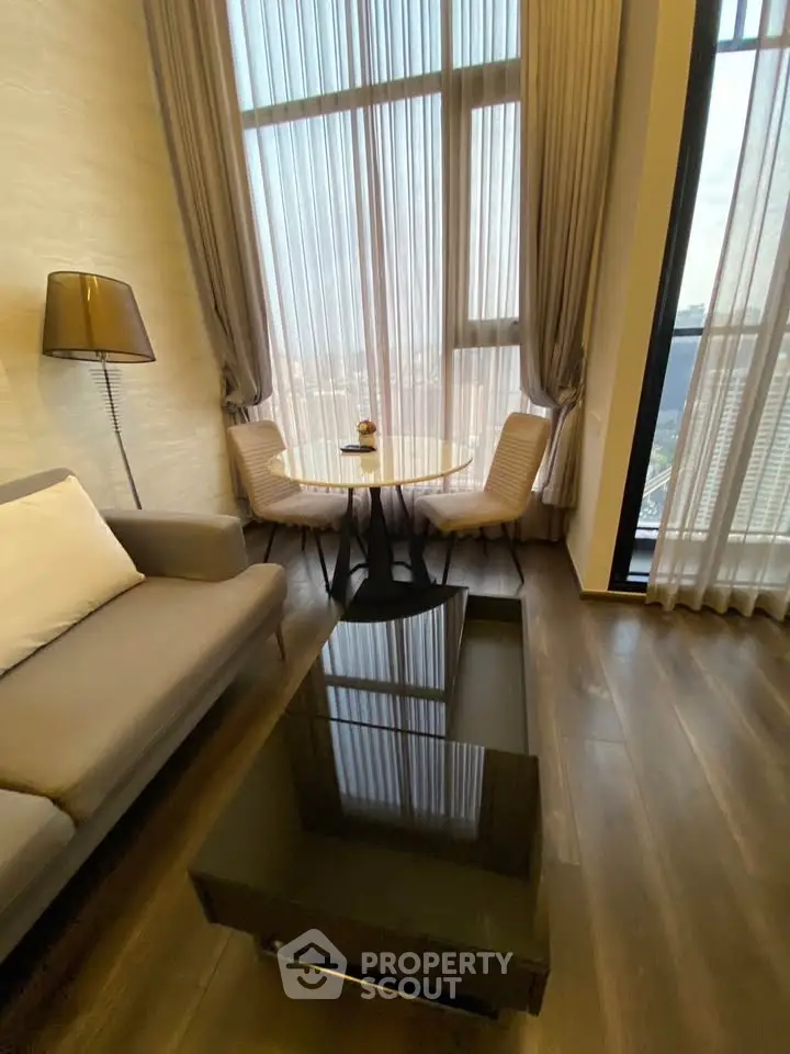 Modern living room with high ceilings and large windows offering stunning city views.
