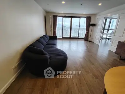 Spacious living room with elegant dark sofa and large windows offering stunning city views.