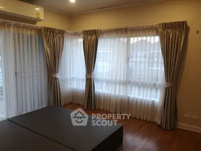 Spacious room with elegant curtains and wooden flooring, perfect for cozy living.