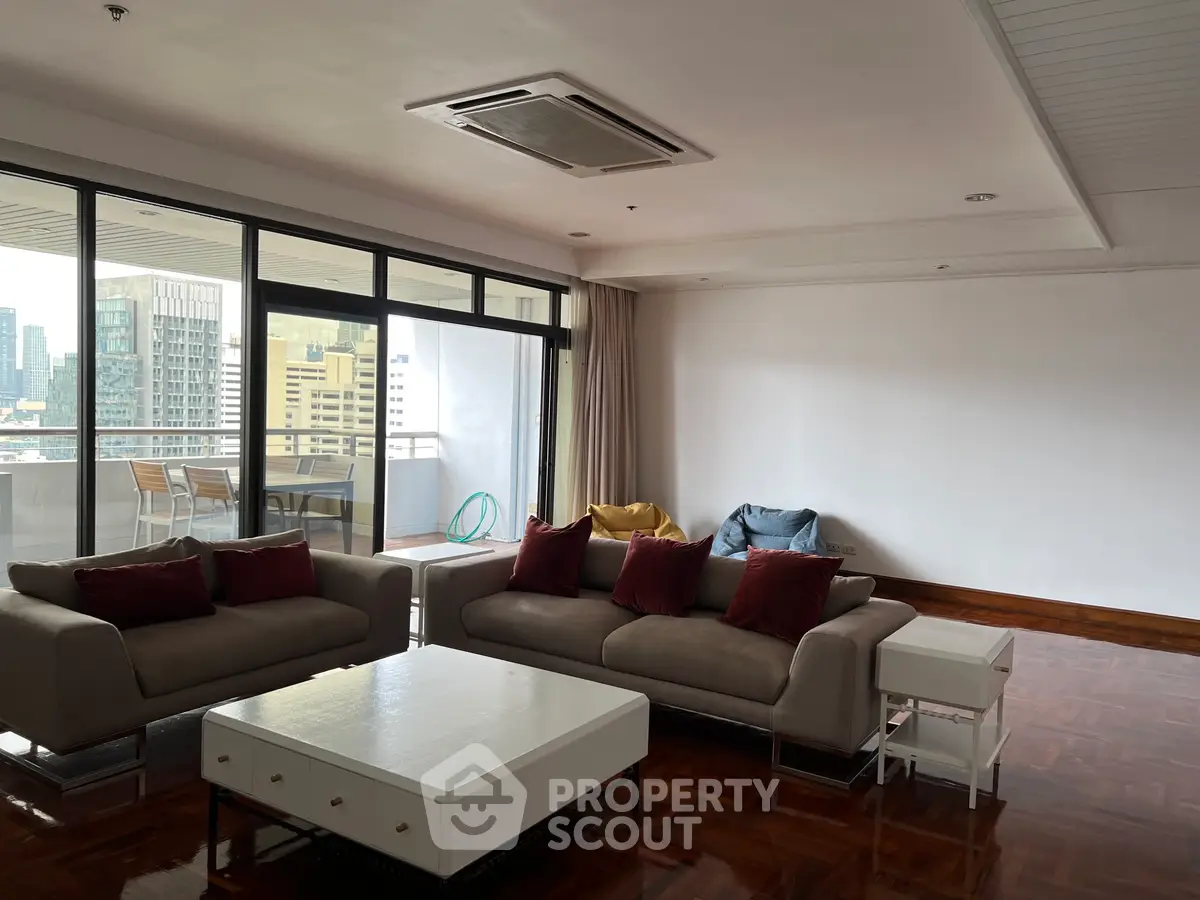 Spacious living room with modern furniture and large balcony offering city views.