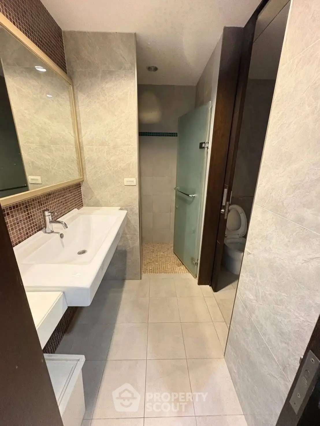 Modern bathroom with sleek design, featuring a spacious sink and glass shower enclosure.