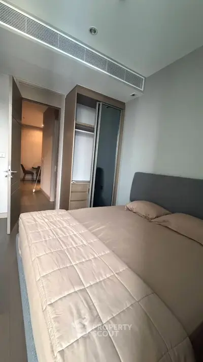 Modern bedroom with sleek design and neutral tones, featuring a comfortable bed and built-in wardrobe.